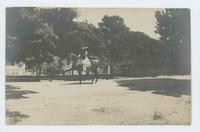 [Woman on horseback in front of house]
