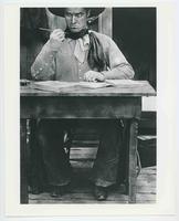 [Comedy photo of Tom Mix seated at a desk looks at pen that does not write]