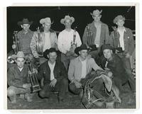 [9 cowboys with trophies in group portrait]