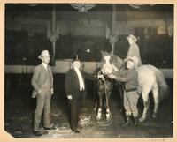 [4 men, 1 on horseback and 2 horses posing for a photograph]