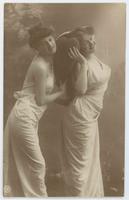 [Two women posed together in simple white gowns with heart prop] 779/2