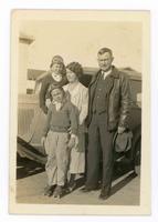 [Man, woman, and two boys standing next to a car]