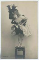 [Woman posed in ruffled dress, large hat, and sequined shoes]