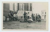 [16 cowboys, 2 cowgirls sitting and standing next to a tent]