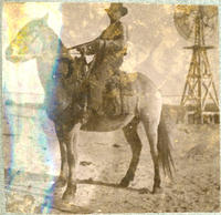 [Cowboy on horse posing in front of windmill]