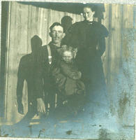 [Man, Woman, & Child pose in front of home]