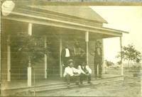 [5 men sitting an standing on porch of house]