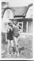 [Two teenaged boys in swimsuits posed in front of ranch house]