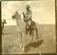 [Cowboy on horse with taut rope tied to saddle horn]