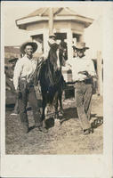 [2 cowboys and a horse posing for a photograph]
