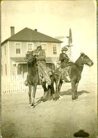 [Man and women each on horseback and in coats in front of house and windmill]