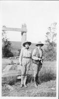 [Two women standing by barbed wire fence]