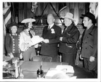 [Foghorn Clancy with 2 men and 2 cowgirls in an office Man in middle accepting cowboy hat from girl