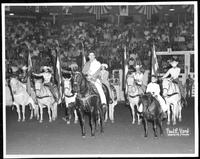 Johnnie Lee Wills [on horseback in rodeo arena with others on horseback]
