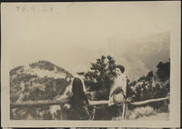 [2 women standing near railing looking at mountains]