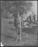 [WWI soldier standing near machinery]